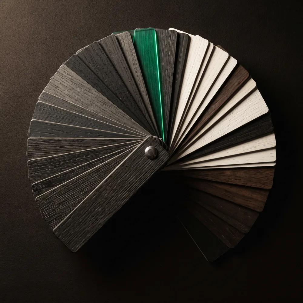 A material sample fan deck splayed open on black, one leaf lit emerald